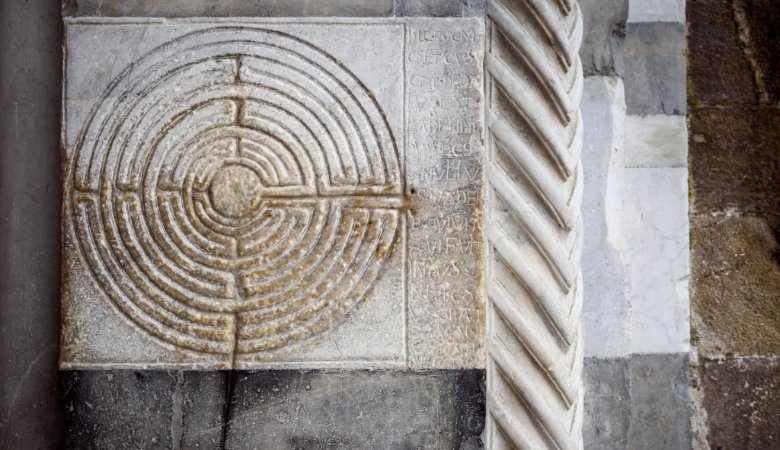 Labyrinth an einer Säule der Kathedrale San Martino in Lucca, Italien. Die lateinische Inschrift greift den Mythos vom Labyrinth auf Kreta auf, „aus dem niemand entkommen kann, der einmal darin ist, außer Theseus“. 
