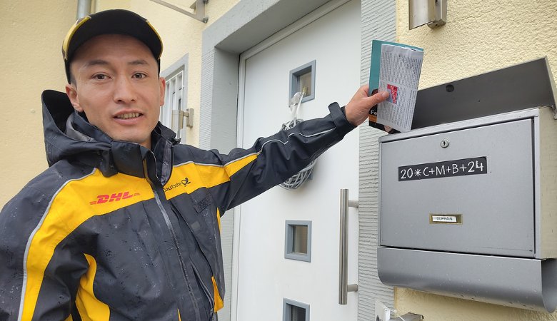 Rafie Mortaza, Zusteller bei der DHL Group und Geflüchteter aus Afghanistan, vor einem Haus in seinem Zustellbezirk in Bonn.