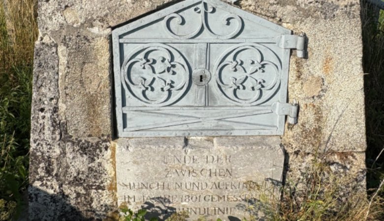 Bei der genaueren Betrachtung der Basispyramide bei Aufkirchen fällt eine verschlossene Metalltür auf, darunter steht eingraviert: „Ende der zwischen München und Aufkirchen im Jahre 1801 gemessenen Grundlinie“.