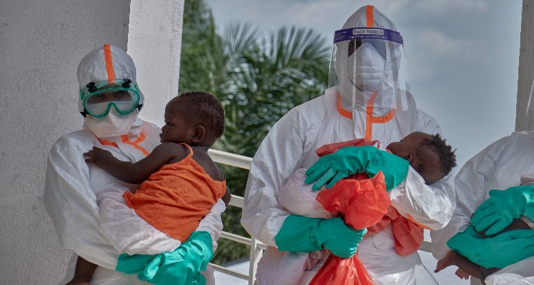 Medizinische Mitarbeiter in Schutzanzügen tragen kleine Kinder in einem Ebola-Behandlungszentrum in Bunia, Kongo.