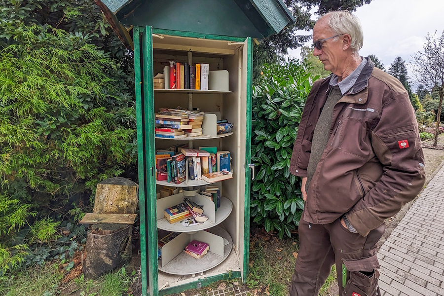 Friedhofsgärtner Uwe Pusback neben einem Bücherschrank, genannt Büchergruft, auf dem Friedhof Lauenburg.