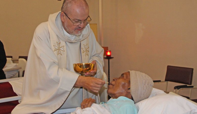 Pater Lagleder reicht einer Frau im Hospiz die Heilige Kommunion. 