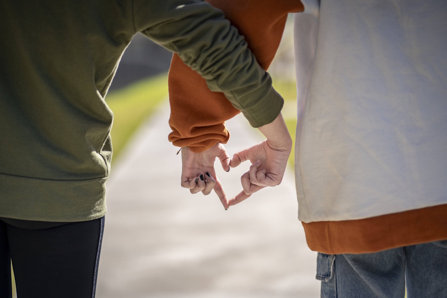 Zwei junge Frauen bilden mit ihren Händen ein Herz – dürfen sie auch in der Kirche zu ihrer Liebe stehen?